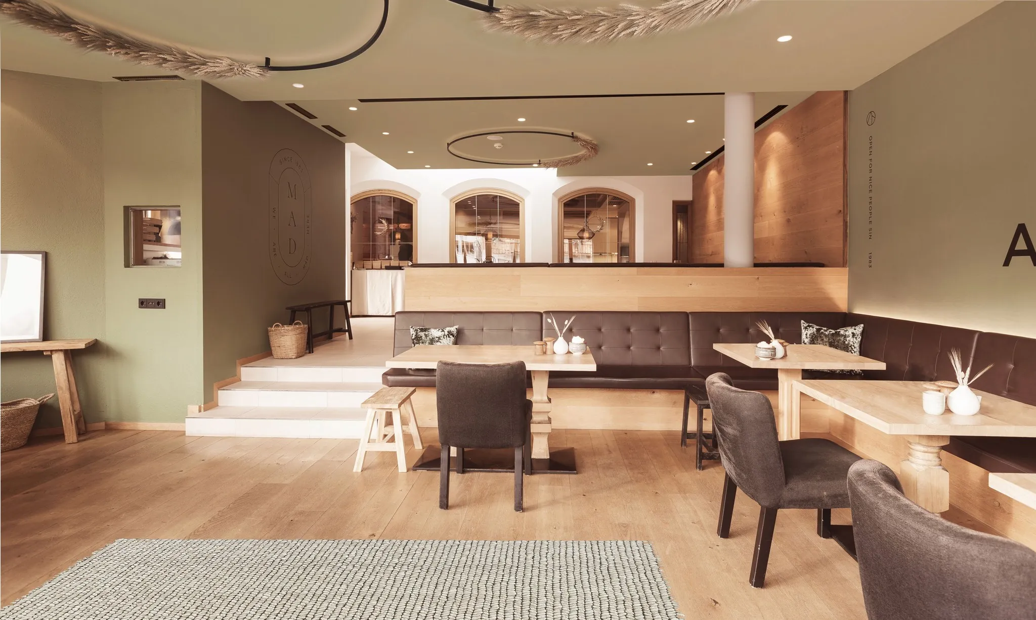 Raum mit Bar, Sitzbänken und Holzboden, im Hintergrund Rundbögen.