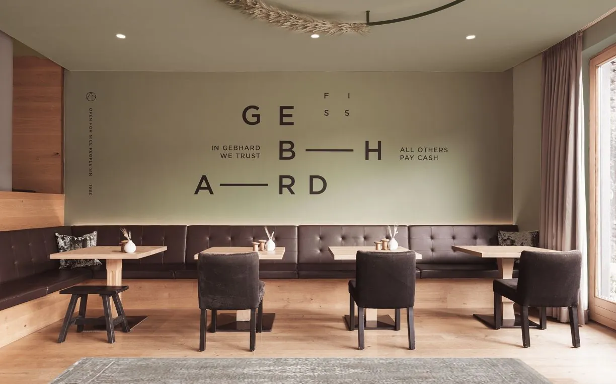 Lederbank und Holztische vor der olivgrünen Wand mit dem GEBHARD-Schriftzug