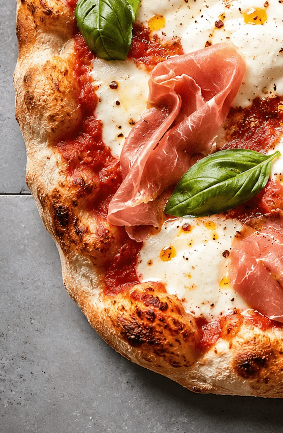 Nahaufnahme einer Pinsa mit Rohschinken, Mozzarella und Basilikum