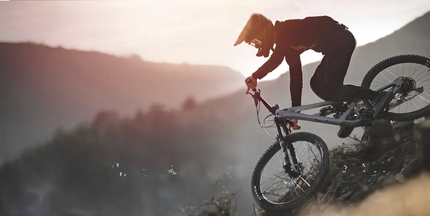 Mountainbiker im Gegenlicht auf einem Grat über dem Tal
