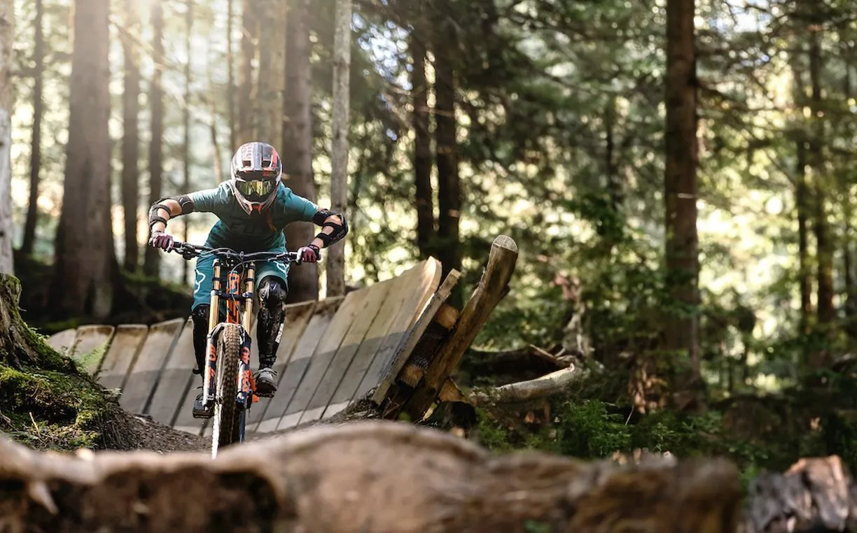 Mountainbiker fährt über eine Holzbrücke im sonnigen Wald