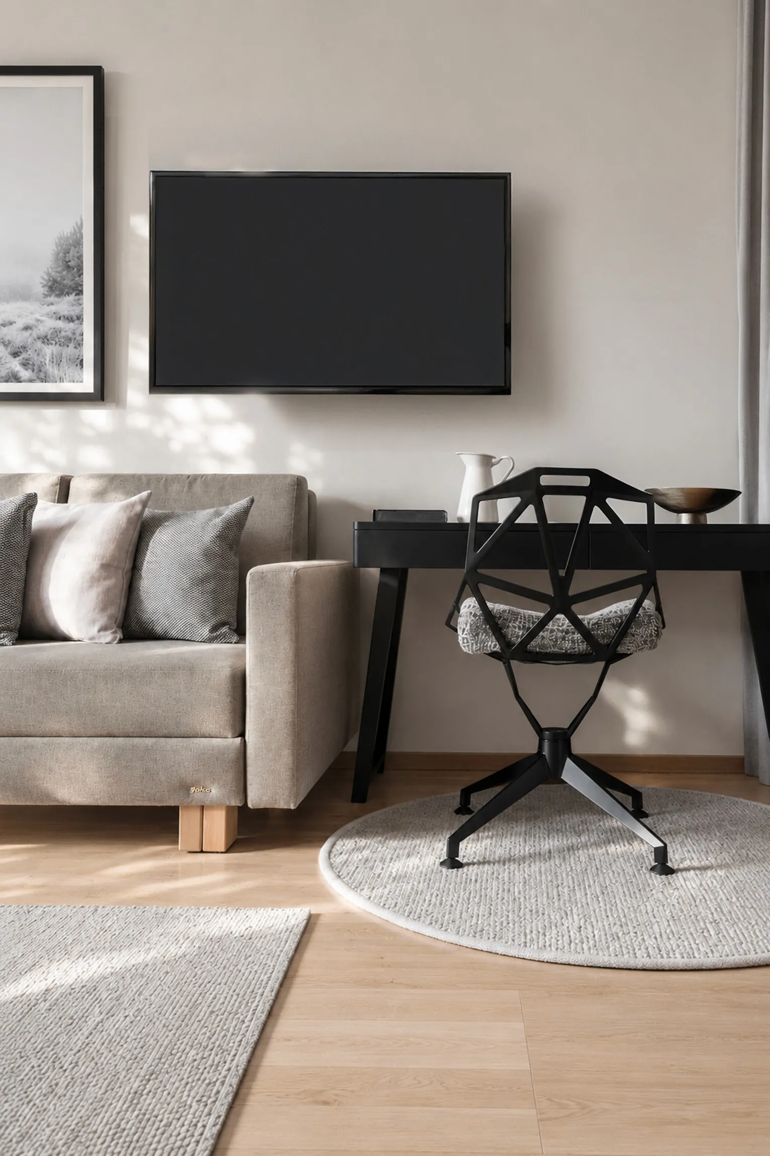 Sitzecke mit grauem Sofa, schwarzem Schreibtisch und rundem Teppich