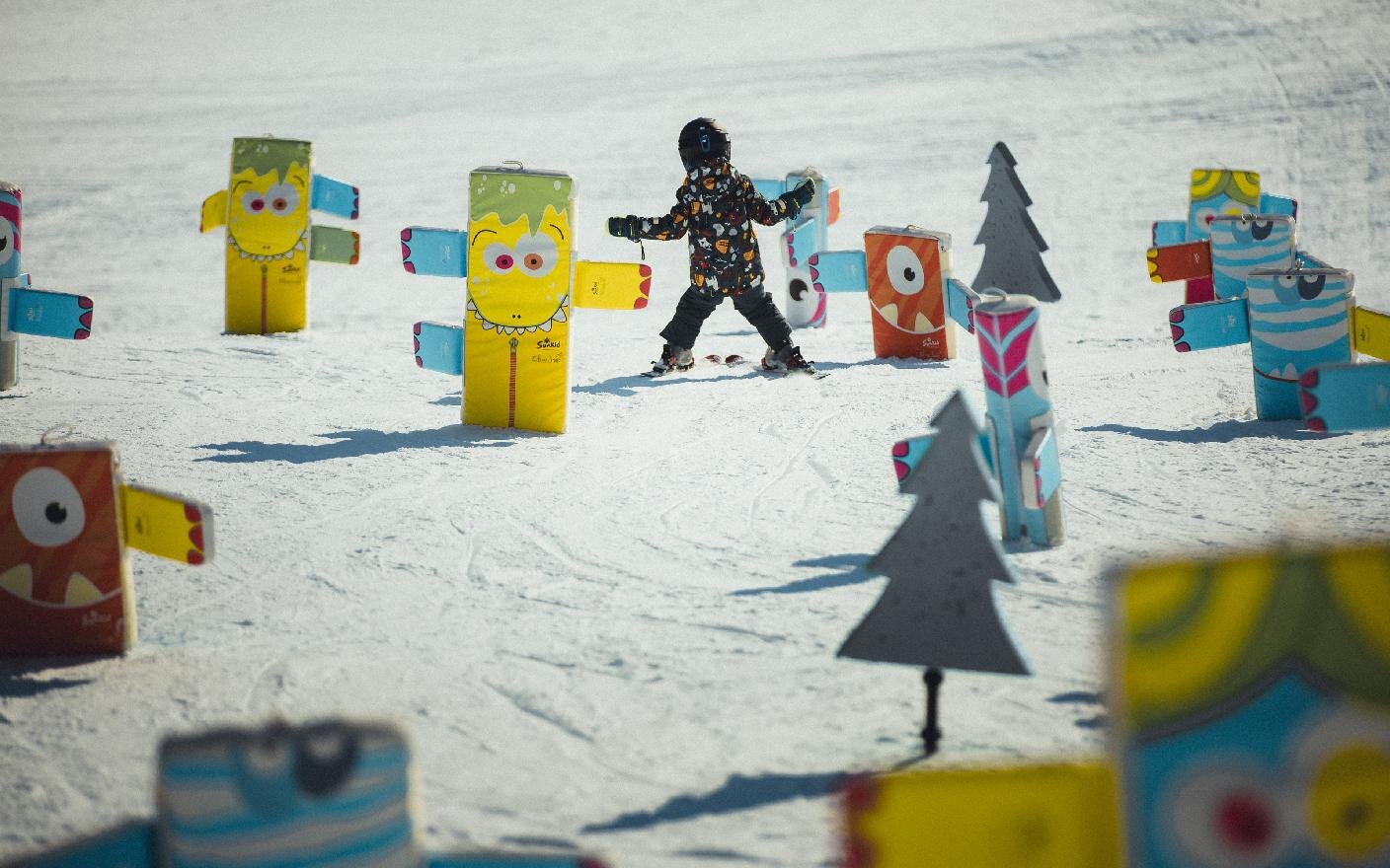 Kind fährt im Schneepflug durch einen Parcours aus bunten Polsterfiguren