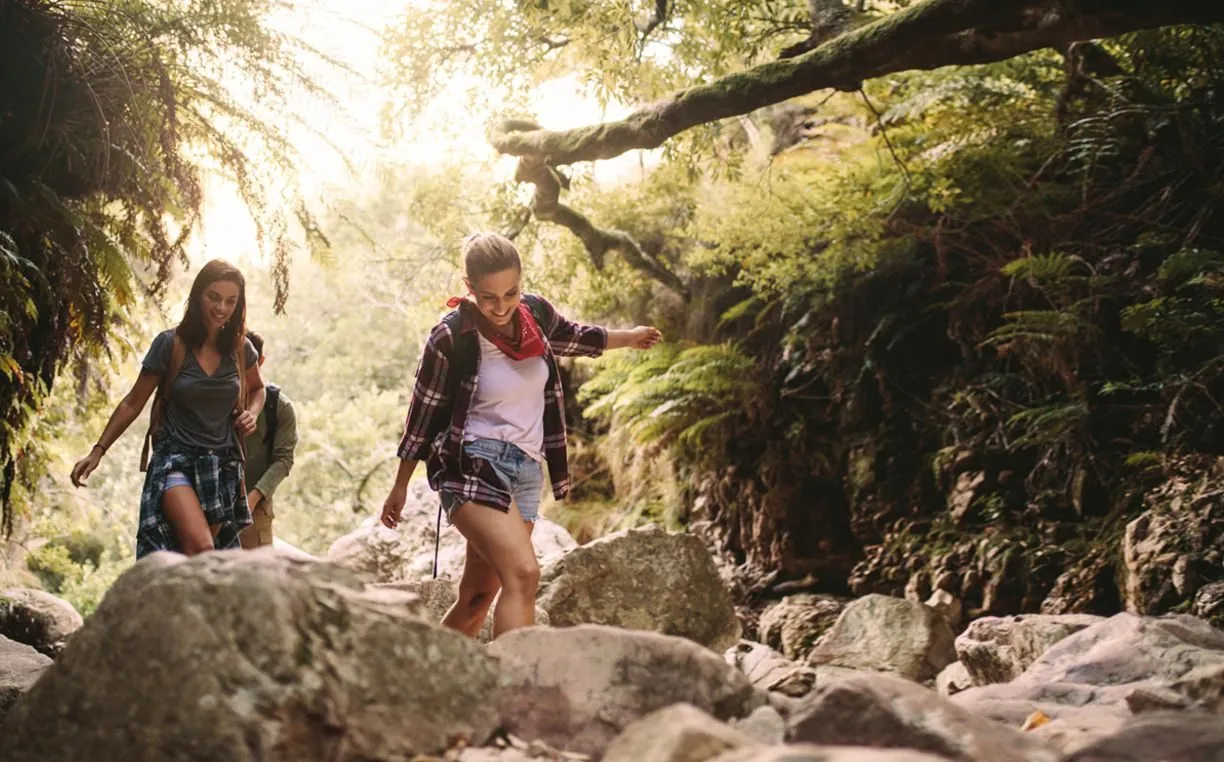 Zwei Wanderinnen auf einem Steig durch eine grüne Klamm