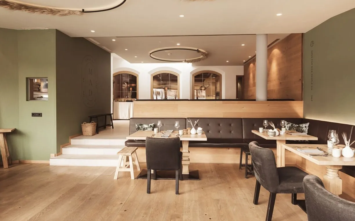 Lounge im Hotel Gebhard mit Holztischen, Bänken und Rundbögen