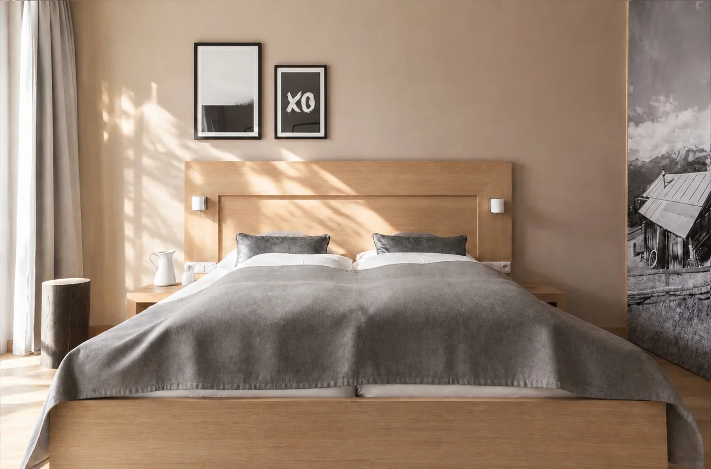 Doppelbett mit Holzkopfteil, dahinter der offene Badbereich mit Waschtisch und großem Bergfoto an der Wand