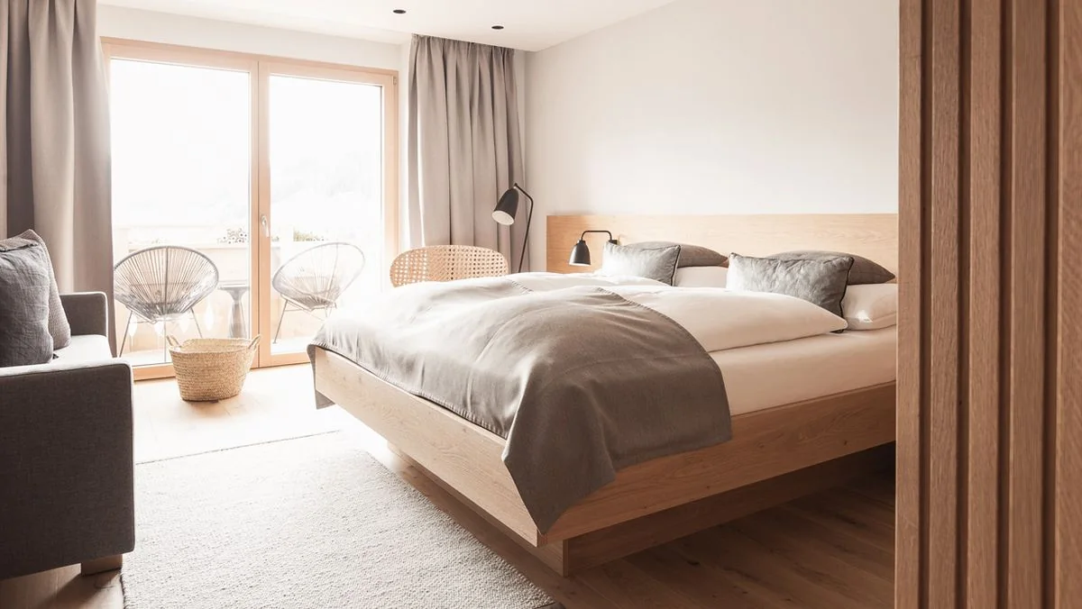 Doppelbett neben der Balkontür, dahinter eine Wand aus hellem Holz