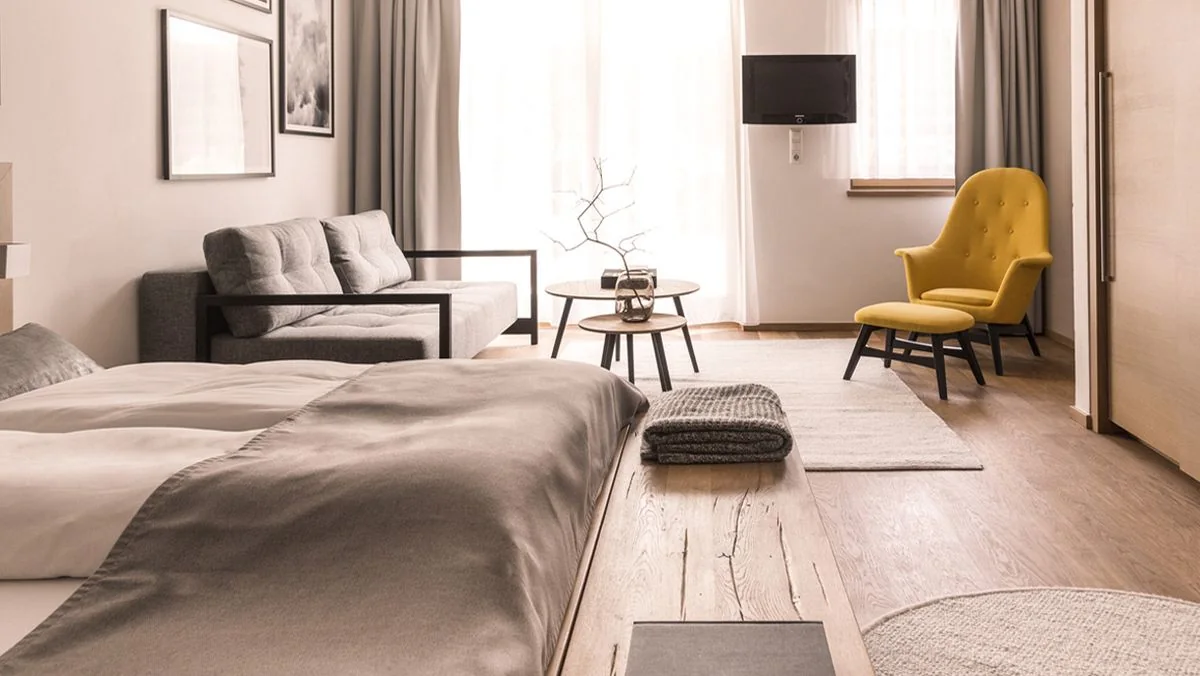 Blick vom Bett auf Sofa, gelben Sessel und Fernseher