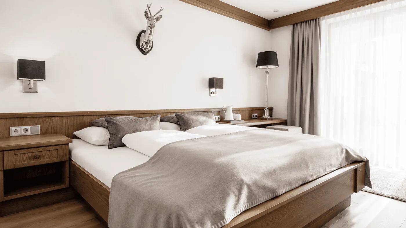 Doppelbett vor der Holzvertäfelung mit silbernem Hirschkopf
