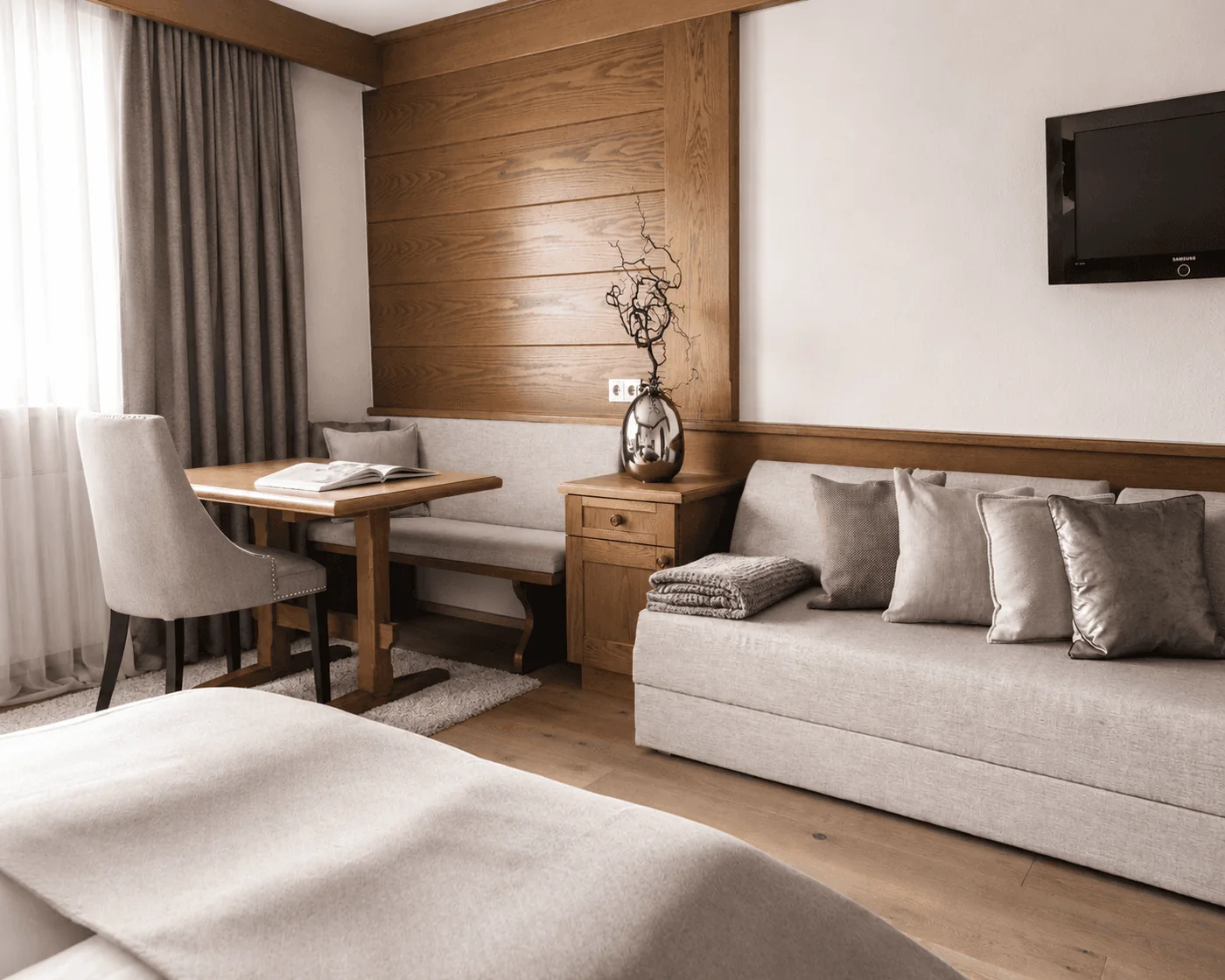 Eckbank mit Tisch und langes Sofa mit Kissen vor der Holzwand